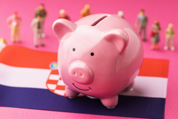 Piggy bank, Croatian flag and plastic toy men on a colored background, the concept on the theme of income of the population of Croatia