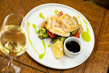 fried squid with vegetables, potatoes and lemon. Served with a glass of wine