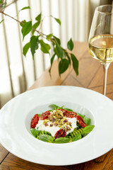 fusili pasta with sun-dried tomatoes and mousse garnished with fresh basil