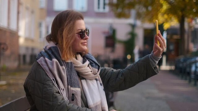 Traveller woman in sunglasses does selfie in the street of old town in autumn, 4k 60p slow motion