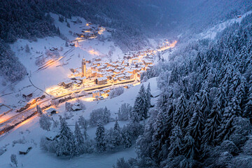 Trees covered with snow in the winter forest surrounding the alpine village at Christmas, Valgerola, Valtellina, Lombardy, Italy