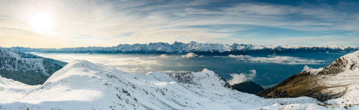 Snowcapped mountains surrounding Alpe Rogneda and Orobie Alps during a misty sunrise in autumn, Rhaetian Alps, Lombardy, Italy
