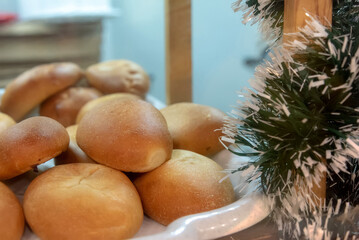 Group of puffy ruddy handmade pies on the plastic tray in the showcase with New Year decoration