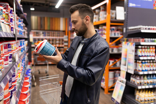 male buyer chooses paint in a hardware store, Concept of finishing exterior and interior walls