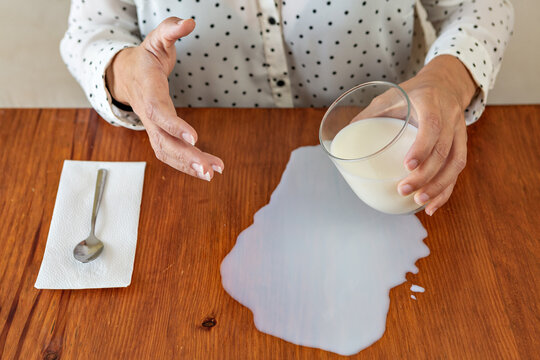 Mujer derrama un vaso de leche en la mesa