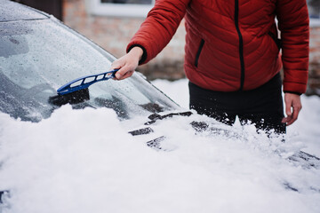 Man cleaning car from snow and ice with brush and scraper tool during snowfall. Winter emergency....