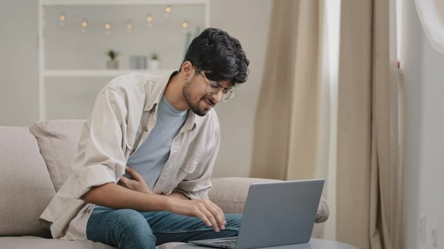 Young guy freelance business man at home working with laptop feels pain abdomen discomfort diarrhea liver problems appendicitis symptoms indigestion stomach spasm ache suffers from poisoning disease
