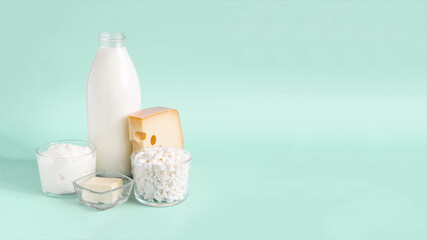 Fototapeta na wymiar Advertising banner with dairy products. Milk, kefir, sour cream, cheese, butter and cottage cheese in a glass container on a light background place for text
