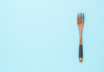Vintage wooden fork with rope on the handle on a blue background. A place for your text. Flat lay.