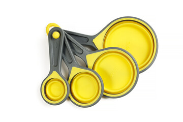 Set of silicone yellow measuring cups and measuring spoons, kitchenware for cooking, isolated on white background close-up