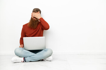 Young reddish caucasian man with laptop isolated on white background covering eyes by hands. Do not want to see something