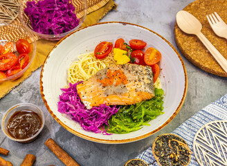 baked salmon steak pasta with tomato, fresh salad and sauce in a bowl on marble background top view