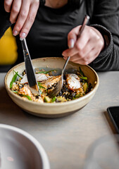 woman hand eating donburi with chicken and rice using knife and fork fom bowl