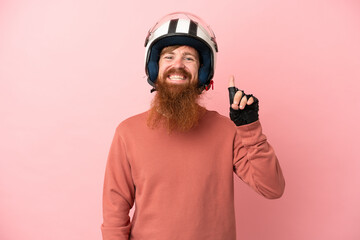 Young reddish caucasian man with a motorcycle helmet isolated on pink background pointing up a great idea