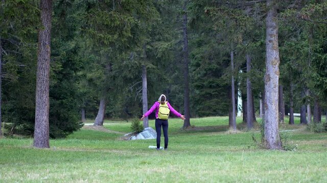 Medium shot woman with open arms breathes the energy of the forest. Immersed in the wild nature. Video 4K