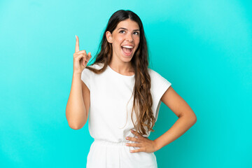 Young caucasian woman isolated on blue background pointing up and surprised