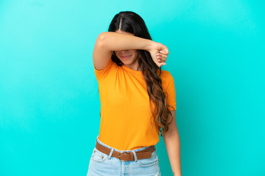 Young caucasian woman isolated on blue background covering eyes by hands
