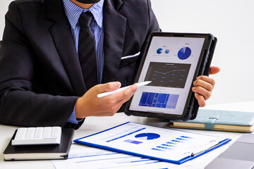 Male accountant calculates last quarter earnings figures and points to tablet to present online documents, business man checking company income and finance documents, modern business man concept.