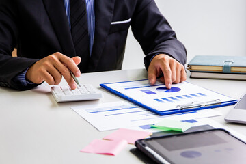 Male accountant calculates last quarter's earnings figures and points to documents to present, business man checking company income and finance documents, modern business man concept.