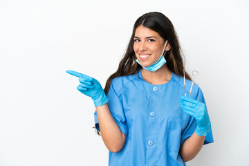 Dentist woman holding tools over isolated white background pointing finger to the side