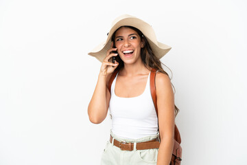 Young caucasian woman wearing a Pamela in summer holidays isolated on white background keeping a conversation with the mobile phone