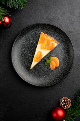 tangerine dessert garnished with tangerine wedges and mint, served on a black plate. dish on black christmas background