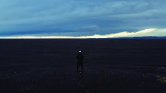 Flying out from back of man in black jacket on volcanic field, Iceland