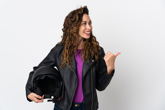 Young caucasian woman holding a motorcycle helmet pointing to the side to present a product
