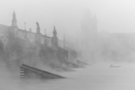 An amazing autumn atmosphere, cloudy, foggy and wet. Prague's famous landmark, river and one of many churches in the background.