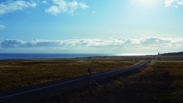 Aerial panoramic view of man walking center line of road to mountain range