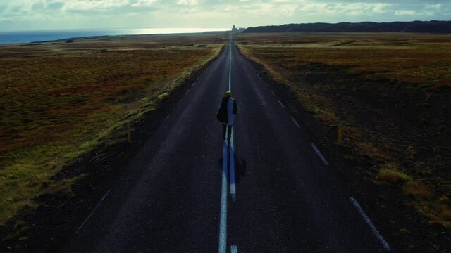 Man walking center of road into horizon, Iceland