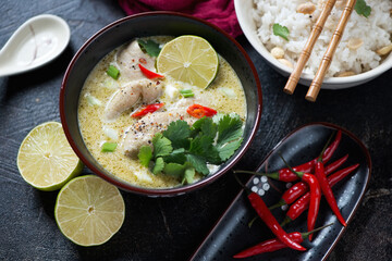 Bowl of green curry with chicken thighs, studio shot on a dark-brown stone background, middle closeup
