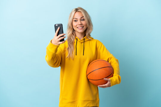 Young Russian woman playing basketball isolated on blue background making a selfie