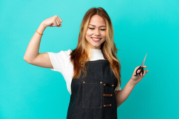 Young hairdresser girl over isolated blue background doing strong gesture