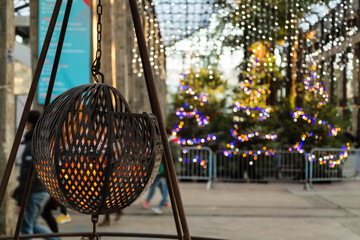 Grande halle sous une verrière avec foyer rougeoyant dans une boule métallique sur trépied et décoration de Noël en arrière-plan. Les Nefs, Machines de l'Île, Nantes