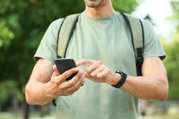 Young male tourist with phone in park