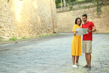 Couple of young tourists with map on city street