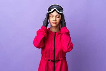 Skier teenager girl with snowboarding glasses over isolated purple background with headache