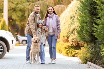 Happy family with Labrador dog walking on street
