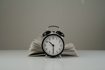 black alarm clock and open book