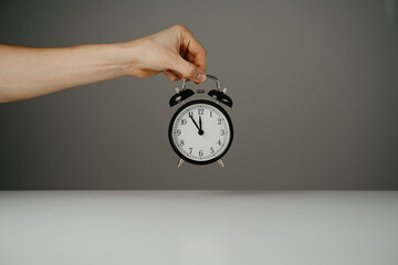 Hand holding black alarm clock