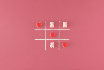 Tic tac toe game with a white chalk and gummy candies on a pink background. Minimal concept.