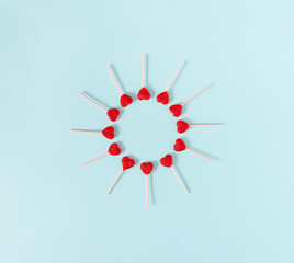 Red heart lollipops shaped into a circle on a pale blue background. Minimal concept.