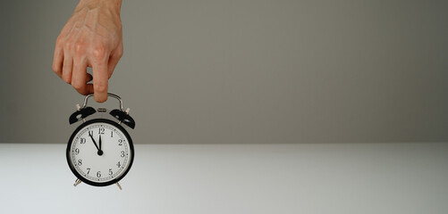 Hand holding black alarm clock