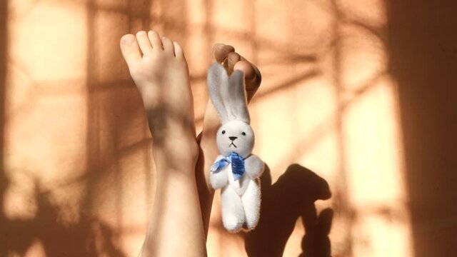 Fashion hipster aesthetic with jeans , bunny toy and female bare foot on orange coral background with shadows lines
