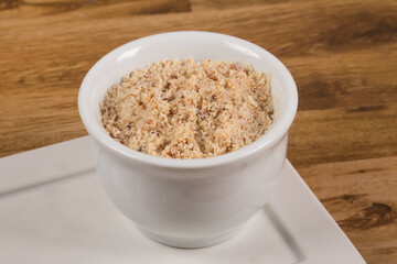 Brazilian Farofa. Manioc Flour into a  white bowl on wooden background.