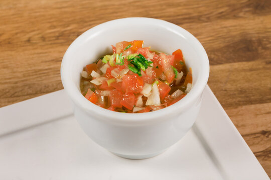 .Vinagrete or Vinaigrette is. a traditional Brazilian sauce made with tomato, pepper, onion, vinegar and parsley. Served in white bowl on wooden background.