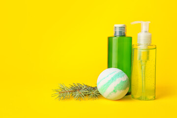 Bath bomb, bottles of cosmetic products and fir branch on color background