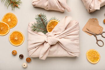 Beautiful Christmas gift wrapped in fabric on light background