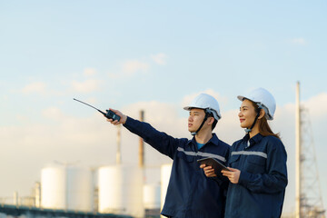 Asian engineers, man and woman are checking the maintenance of the oil refinery factory at evening...